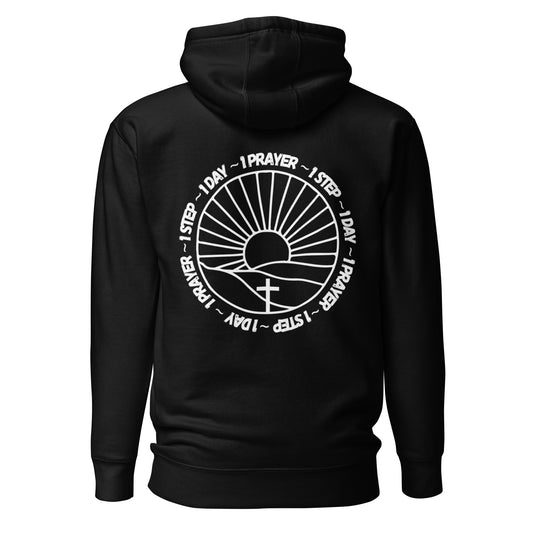 One prayer, one step, one day hooded sweatshirt. There is white lettering surrounding a sun on the horizon, shining on a cross. (Black in color)